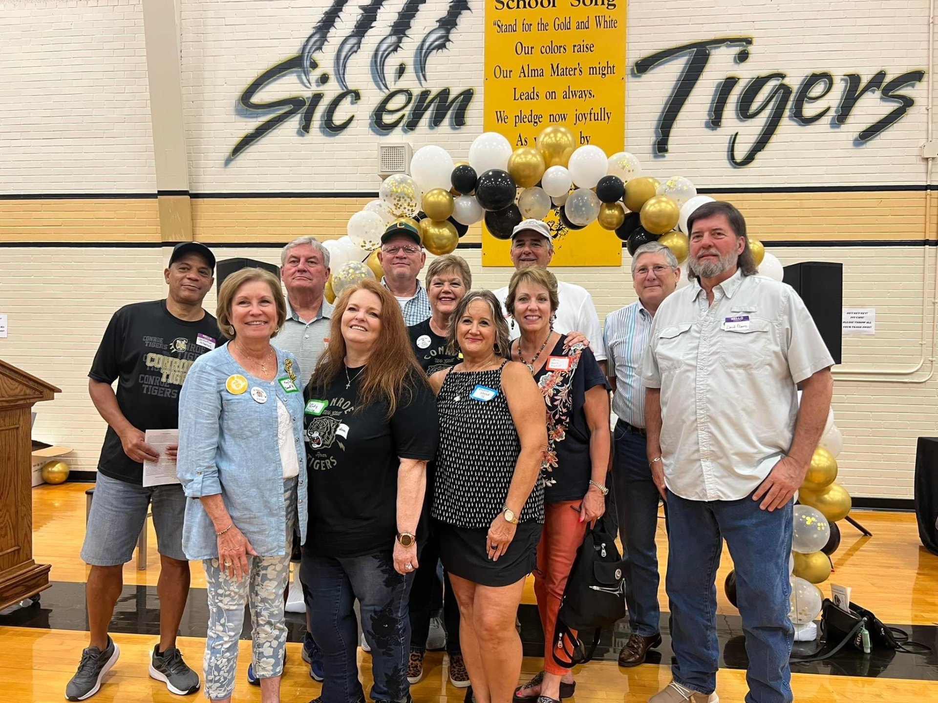 Group of Conroe High alumni in front of Sic 'em Tigers wall